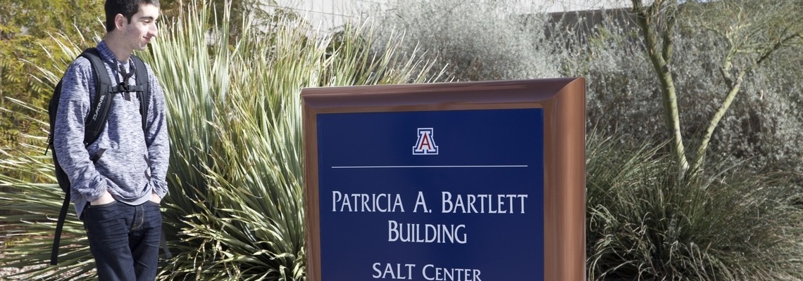 Student passing "Patricia A. Bartlett Building SALT Center" sign on campus.