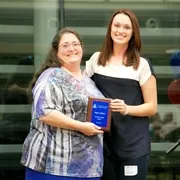 2 women holding an award plaque together