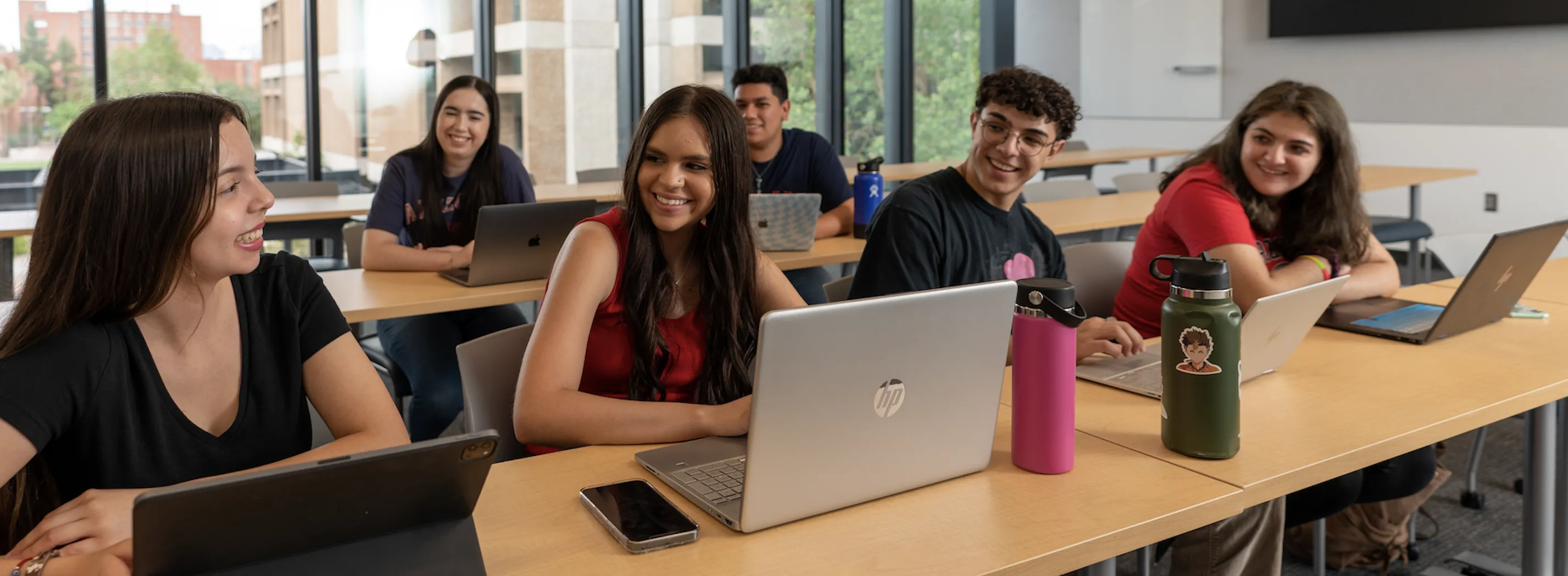 6 students in a workshop room together on their laptops