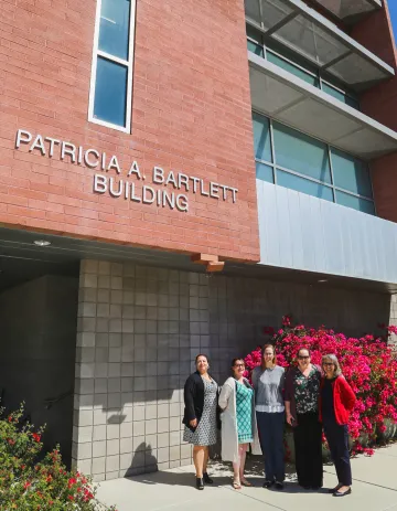 A group of individuals standing in front of the Patricia A. Bartlett Building