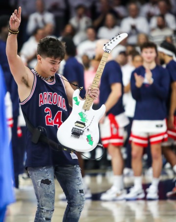 Max Ho performing on a guitar at a basketball game