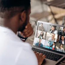 Man at a laptop displaying a video conference call