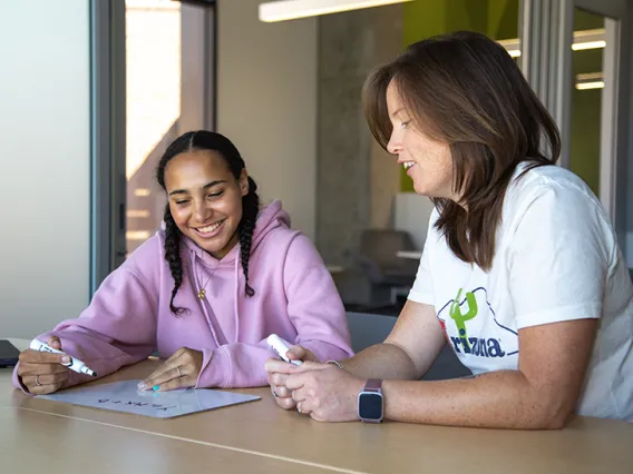 A student and her support specialist sitting together at a table with a small white board and markers